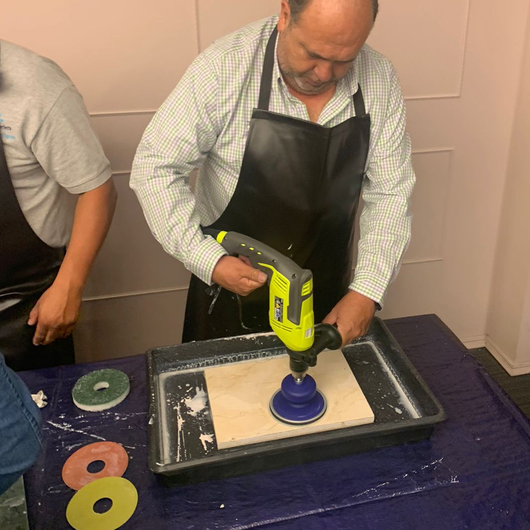 Person using a stone polishing kit with a drill tool on a marble slab